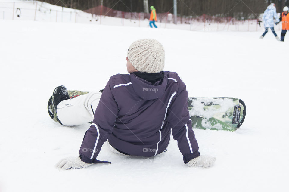 girl sitting on a snowboard in the snow