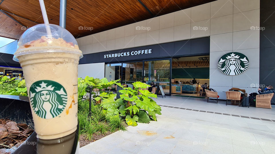 Glass of iced coffee from starbucks in front of the store