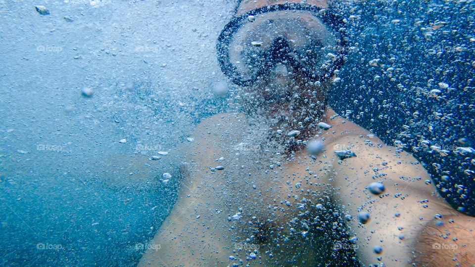 Man diving, male underwater smiling,swimming and relaxing in big blue sea with his camera