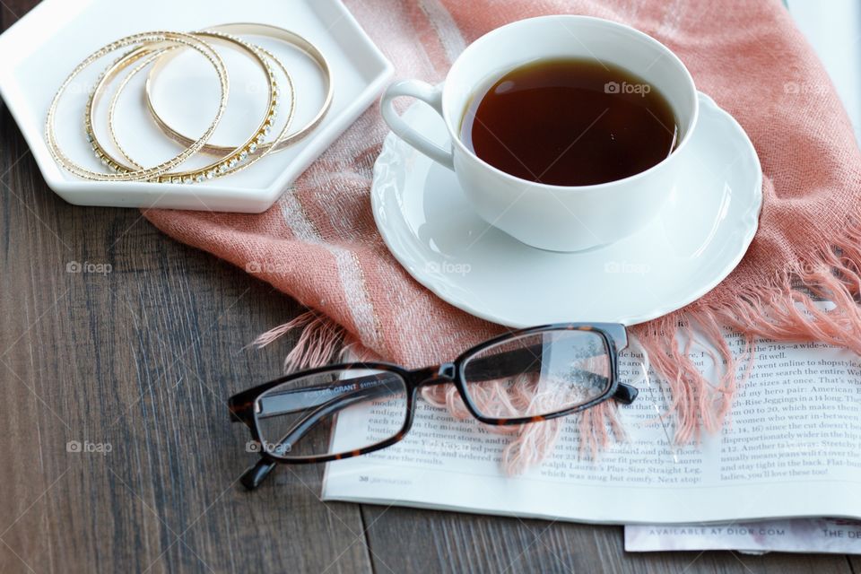 Cup of coffee with eyeglasses and bangles on table