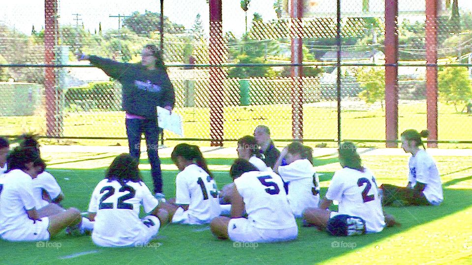 Girls high school soccer team receiving some advice from the coach