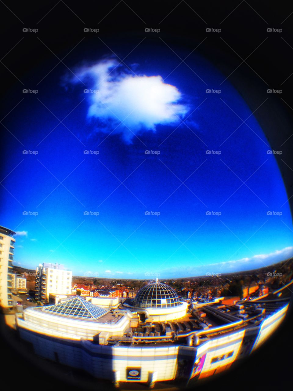 Fisheye view of skyline east London buildings with blue sky and white clouds