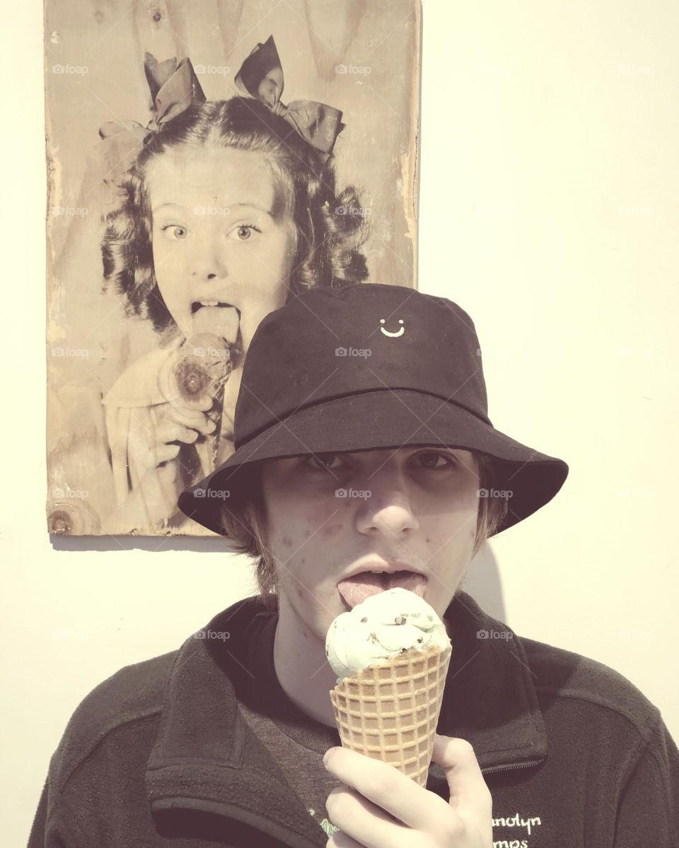 Eating ice cream mimicking a photo in the background, delicious mint chocolate chip in a waffle cone, vintage feeling to the image 