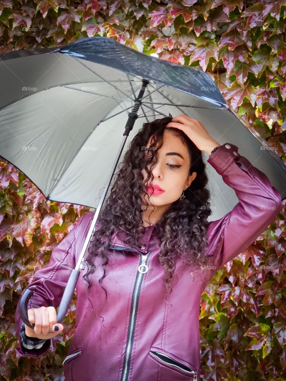 Curly haired girl with an umbrella under the autumn rain