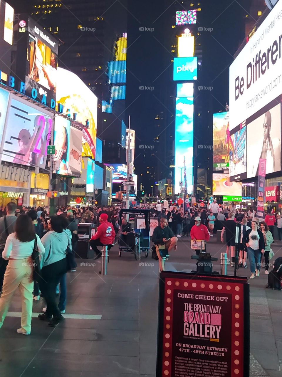 Artists, ticket sellers, tourists meet in Times Square in the middle of buildings and luminous screens