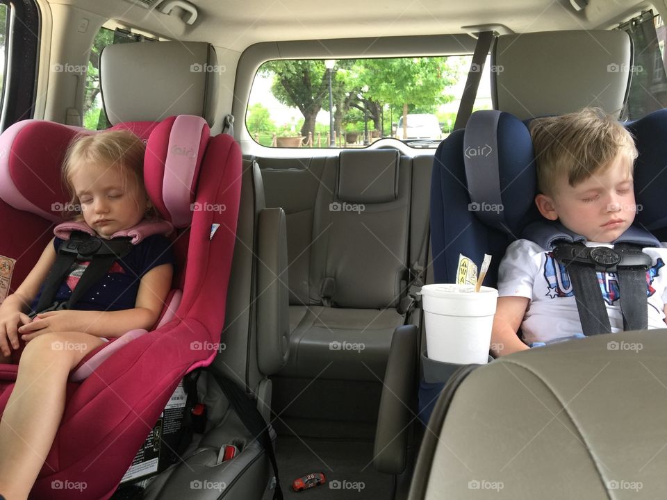 Twins sleeping in car seats. Tired toddlers on the drive home